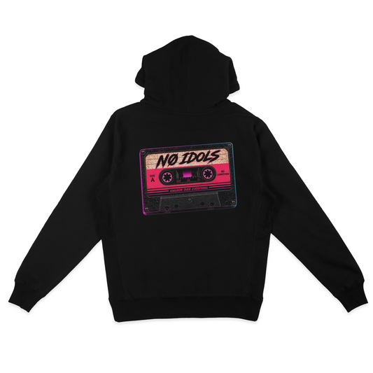 A black pullover hoodie shown from the back, featuring a large graphic print of a retro cassette tape with the text 'NO IDOLS' in black script on a pink and beige cassette body.
