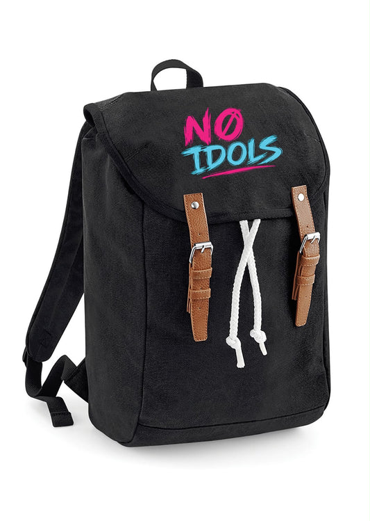 A black canvas backpack with a top flap, featuring the text 'NO IDOLS' in pink and blue graffiti-style lettering on the front. It has brown faux-leather strap details on the sides, a white drawstring, and a black top handle, shown against a plain white background.